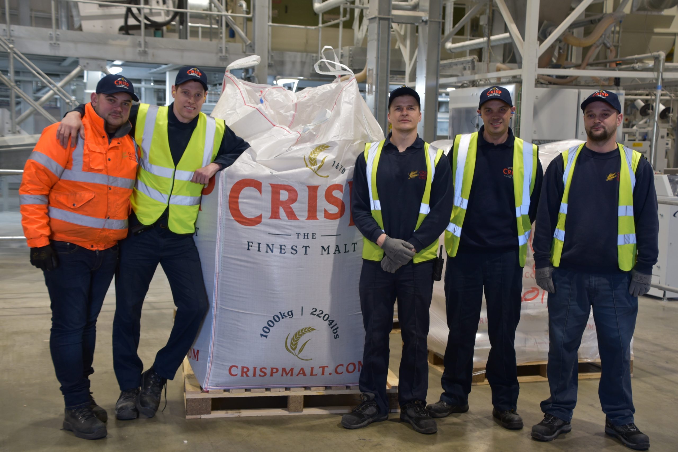 Crisp Malt team in the warehouse at Great Ryburgh, Norfolk, England in front of a large tonne bag of malted barley for brewers and distillers