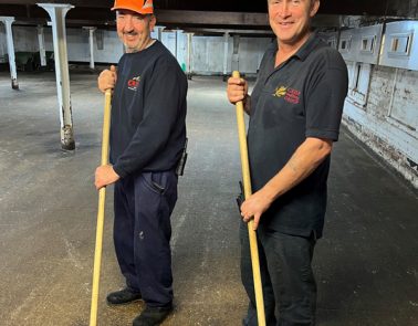 Two floor maltsters holding a wooden dousey, on the traditional malt floorings in Great Ryburgh, Norfolk.