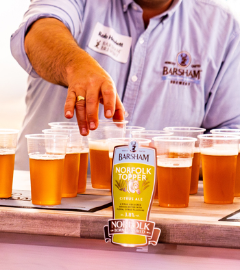 A male reaching for a glass of Norfolk Topper
