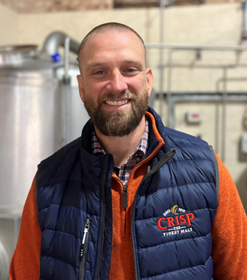 Josh wearing a Crisp Malt uniform, smiling at the camera