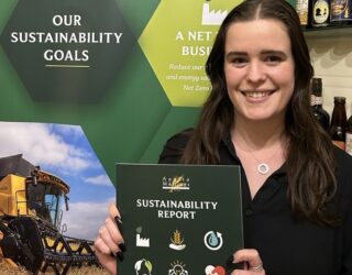Ellie Wood, Sustainability Coordinator at Crisp Malt holds our latest Sustainability Report 2023 brochure.