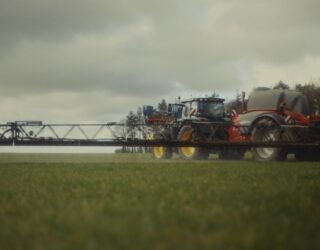 A tractor sprays barley growing on a Norfolk field.