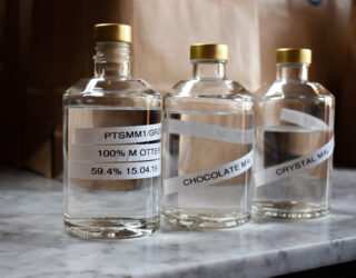 International Whiskey Day 26 - 3 bottles of spirits lined up in a craft distillery.